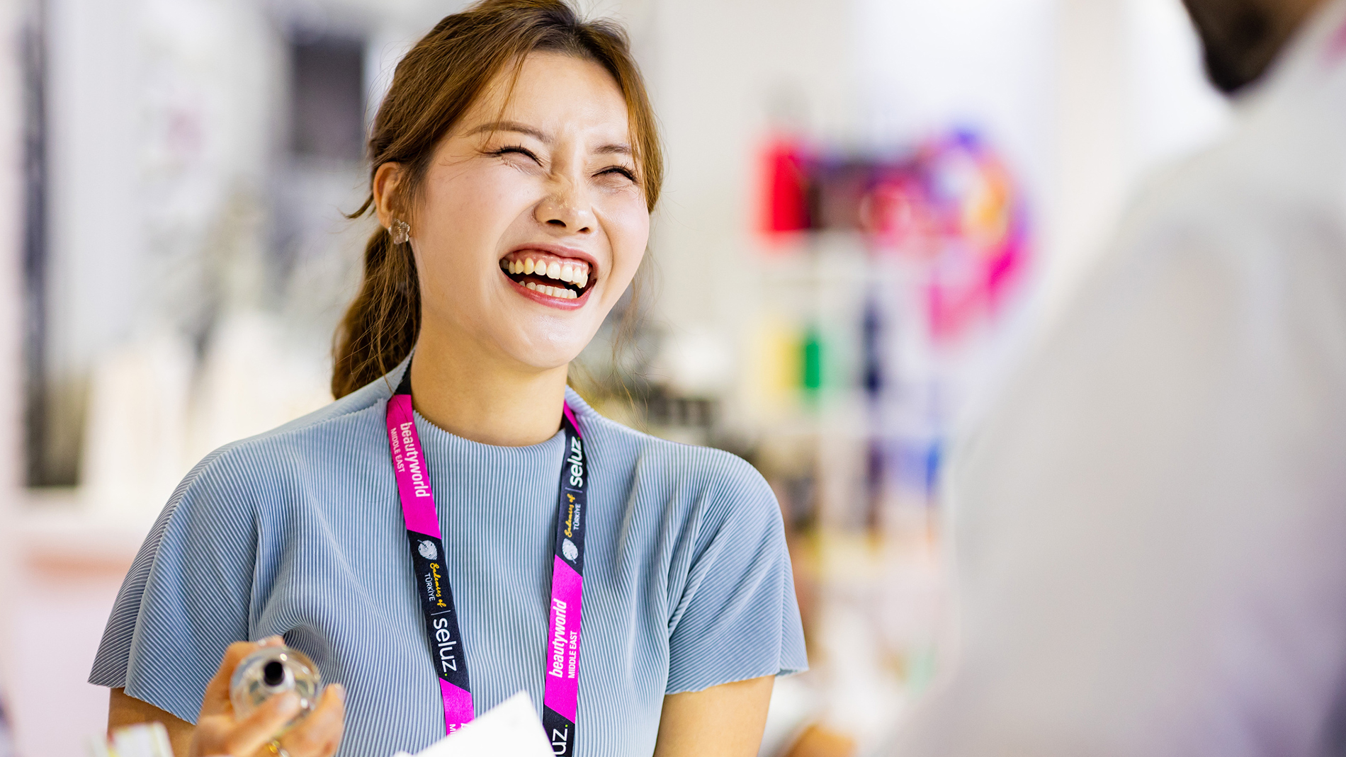 Exhibitor laughing while holding product at Beautyworld Middle East